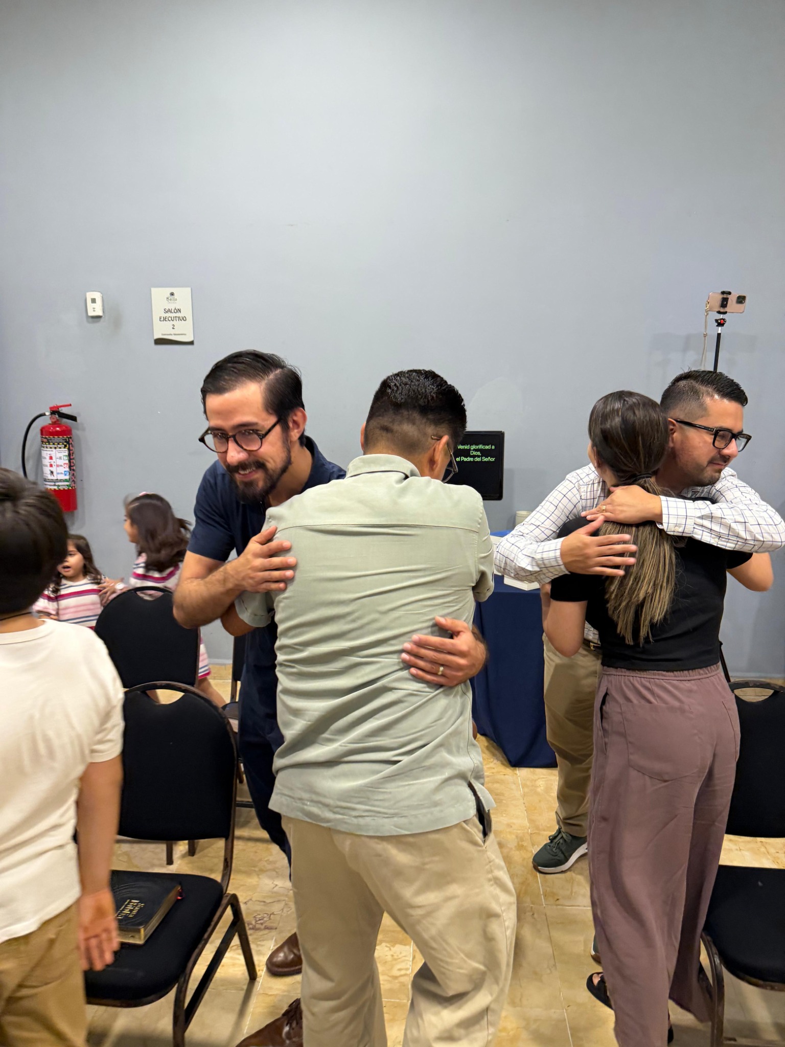 Miembros de la iglesia saludándose con abrazos después de la reunión